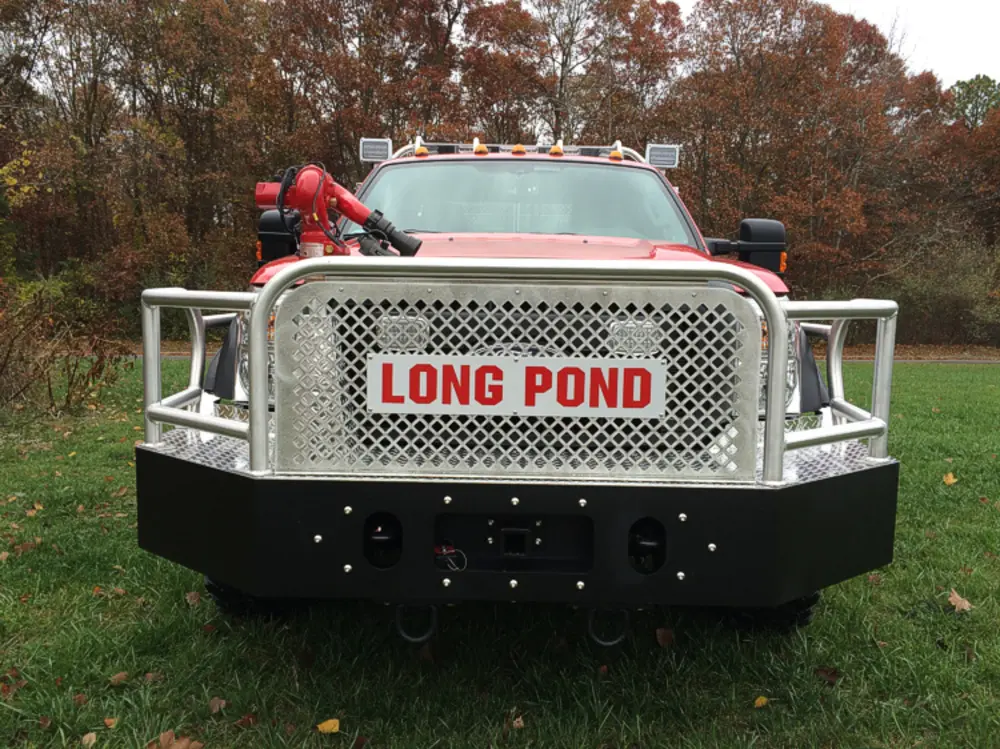Exterior view of small fire truck showing cab, body compartments, and wheel/tire area.