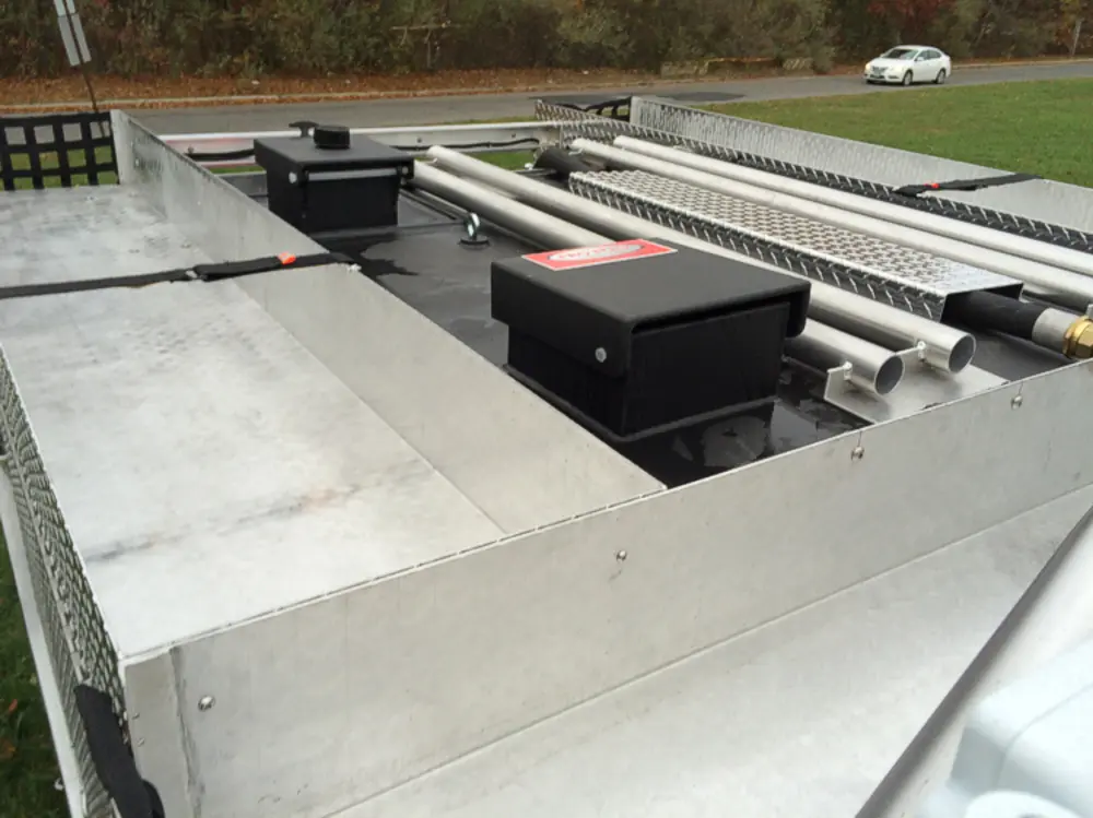 Exterior view of small fire truck showing cab, body compartments, and wheel/tire area.
