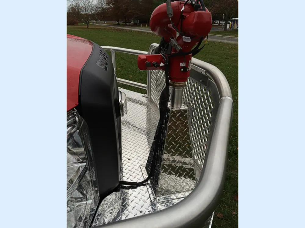 Exterior view of small fire truck showing cab, body compartments, and wheel/tire area.
