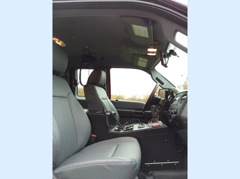 Exterior view of small fire truck showing cab, body compartments, and wheel/tire area.