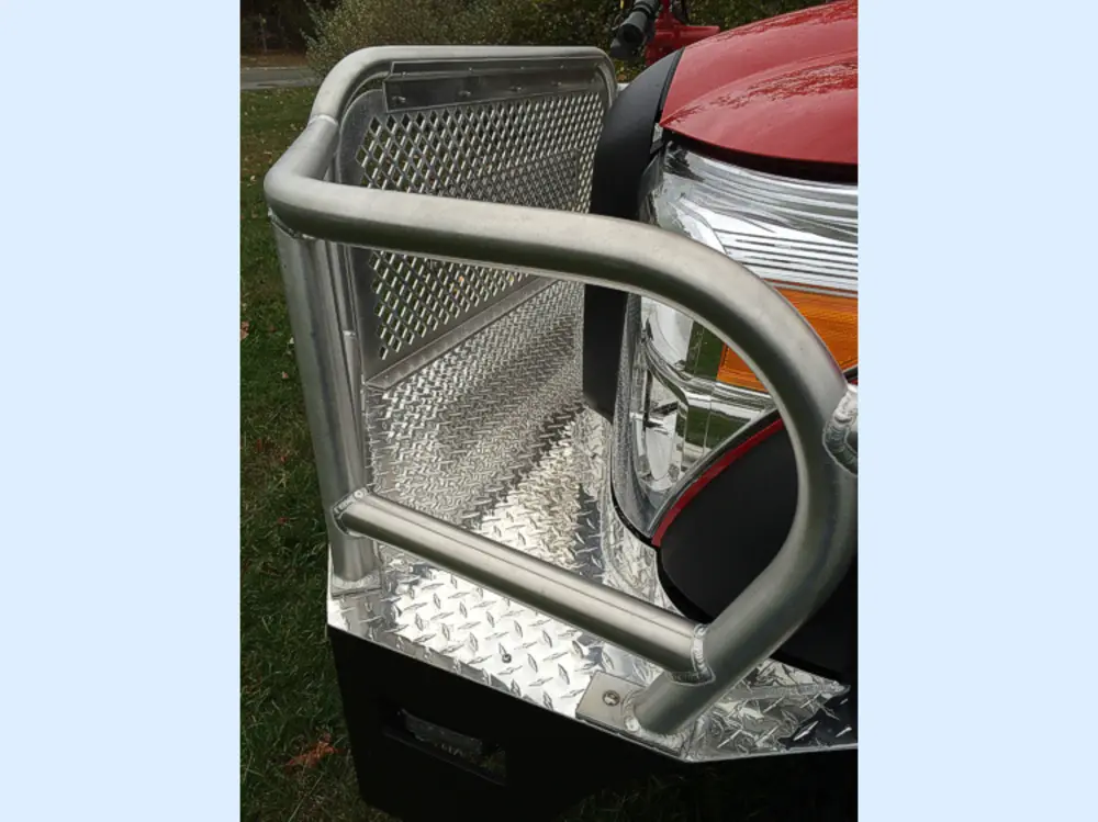 Exterior view of small fire truck showing cab, body compartments, and wheel/tire area.