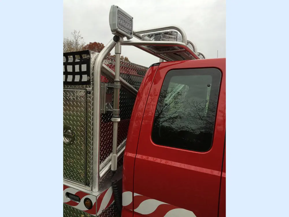 Exterior view of small fire truck showing cab, body compartments, and wheel/tire area.