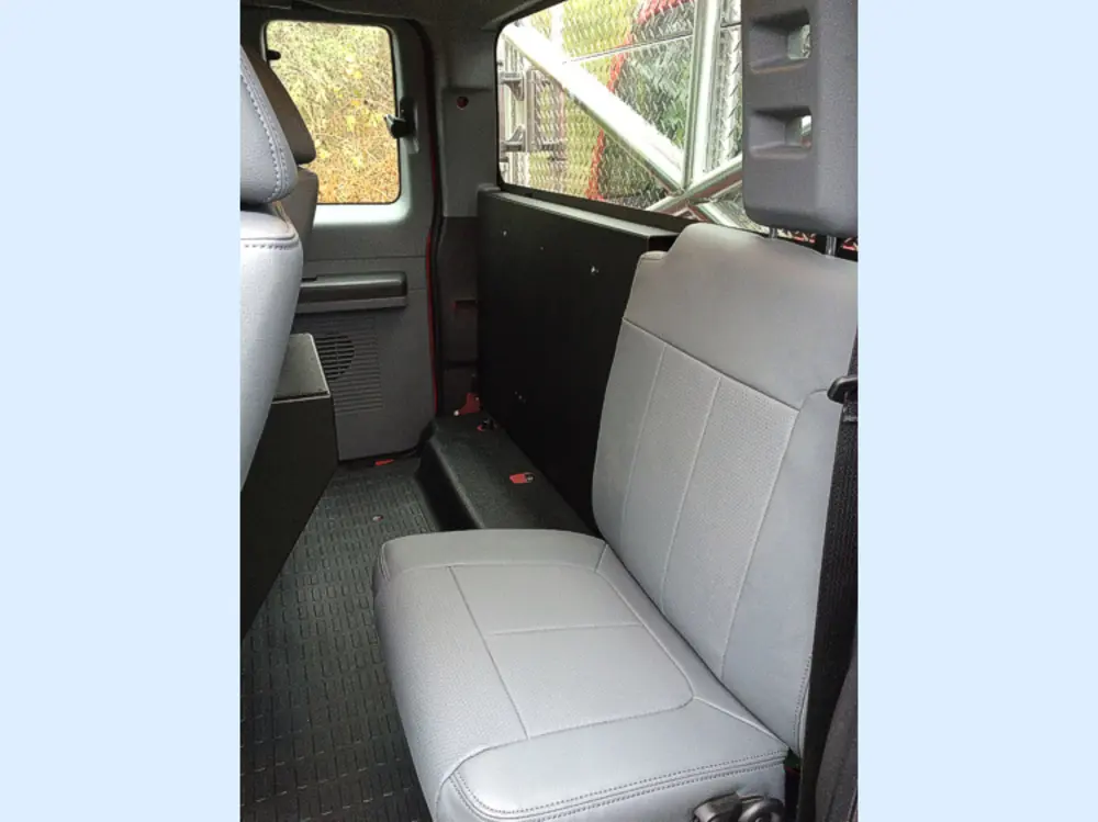 Exterior view of small fire truck showing cab, body compartments, and wheel/tire area.