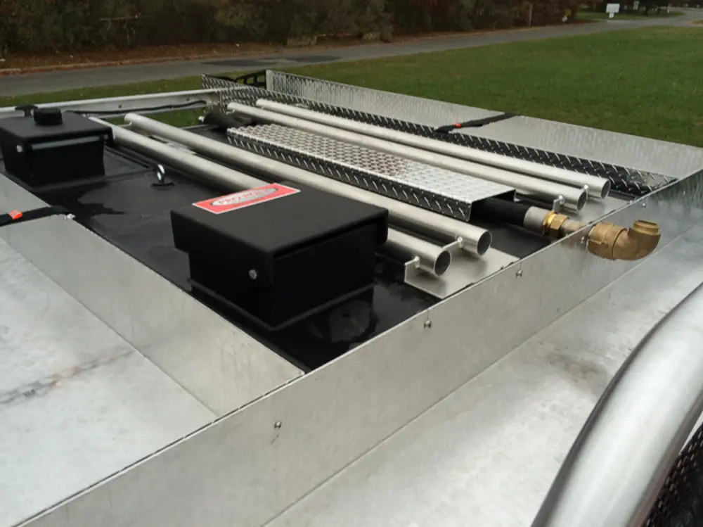 Exterior view of small fire truck showing cab, body compartments, and wheel/tire area.