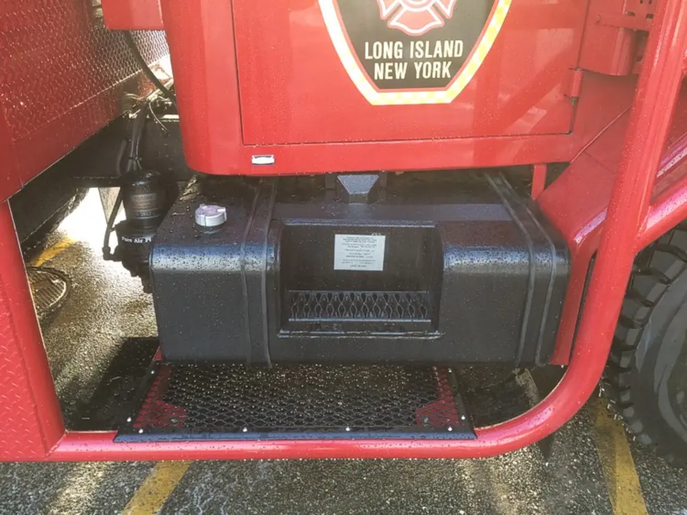 Exterior view of small fire truck showing cab, body compartments, and wheel/tire area.