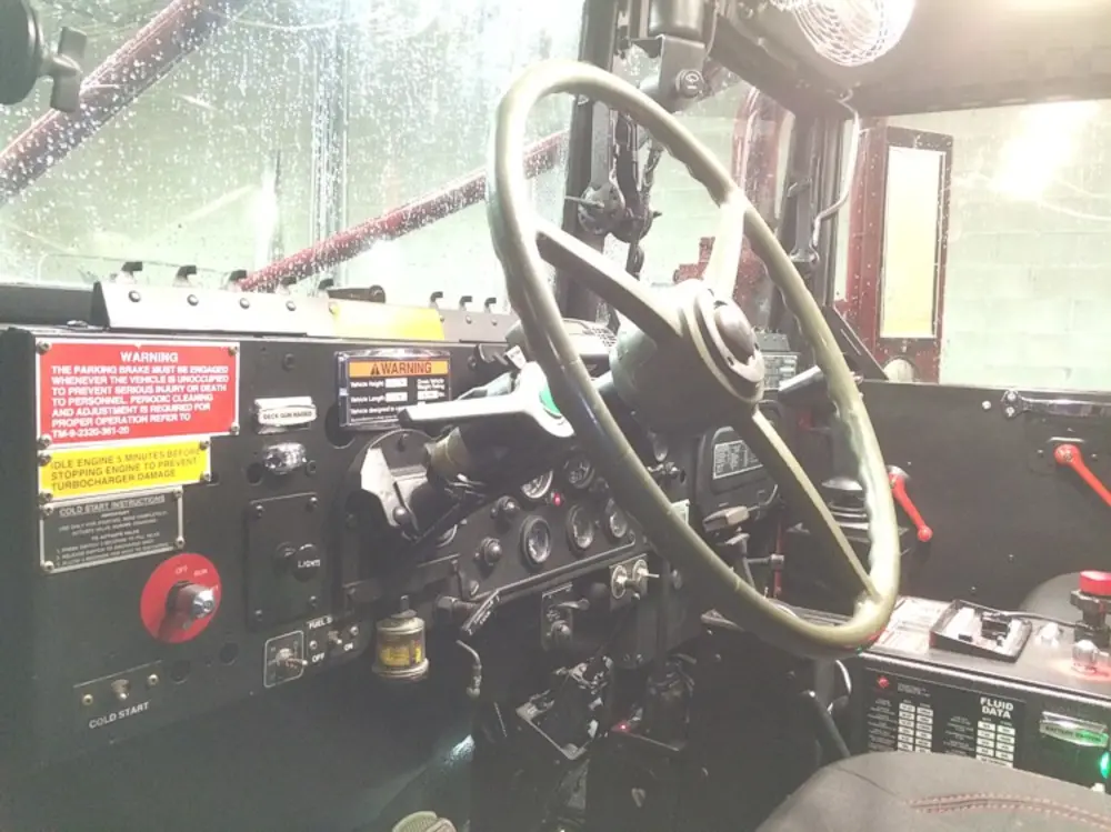 Exterior view of small fire truck showing cab, body compartments, and wheel/tire area.