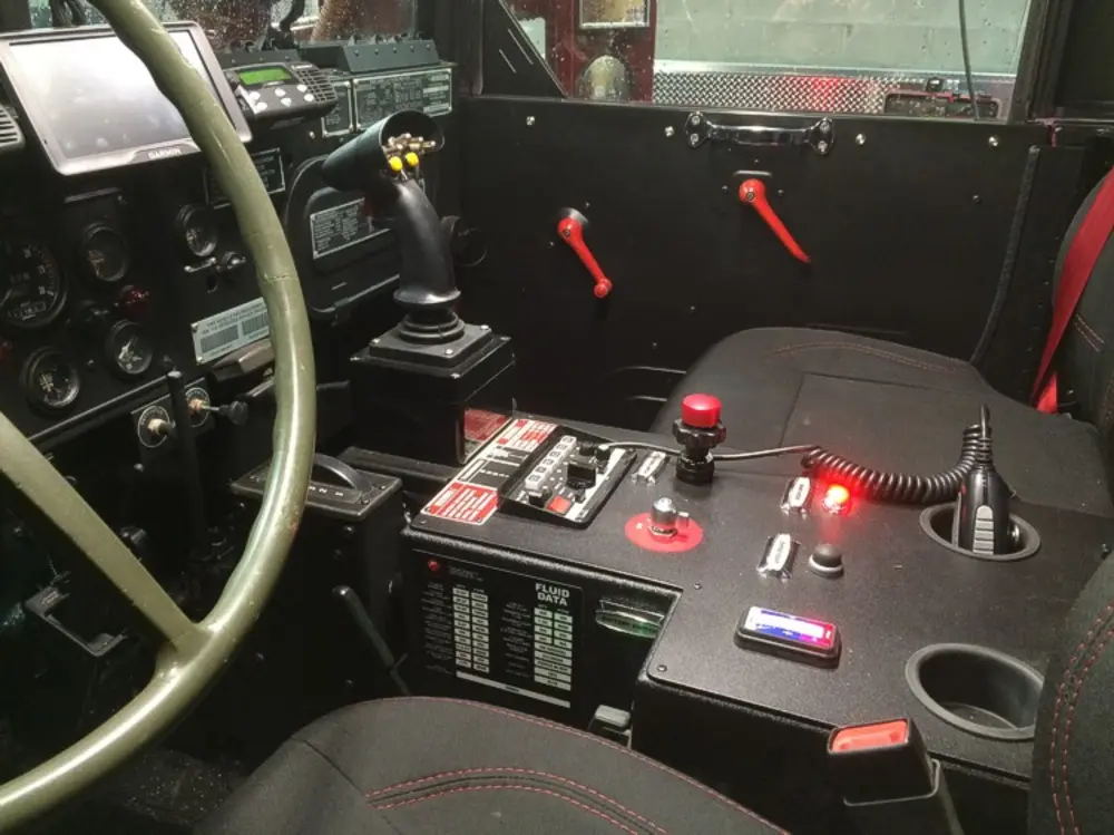 Exterior view of small fire truck showing cab, body compartments, and wheel/tire area.