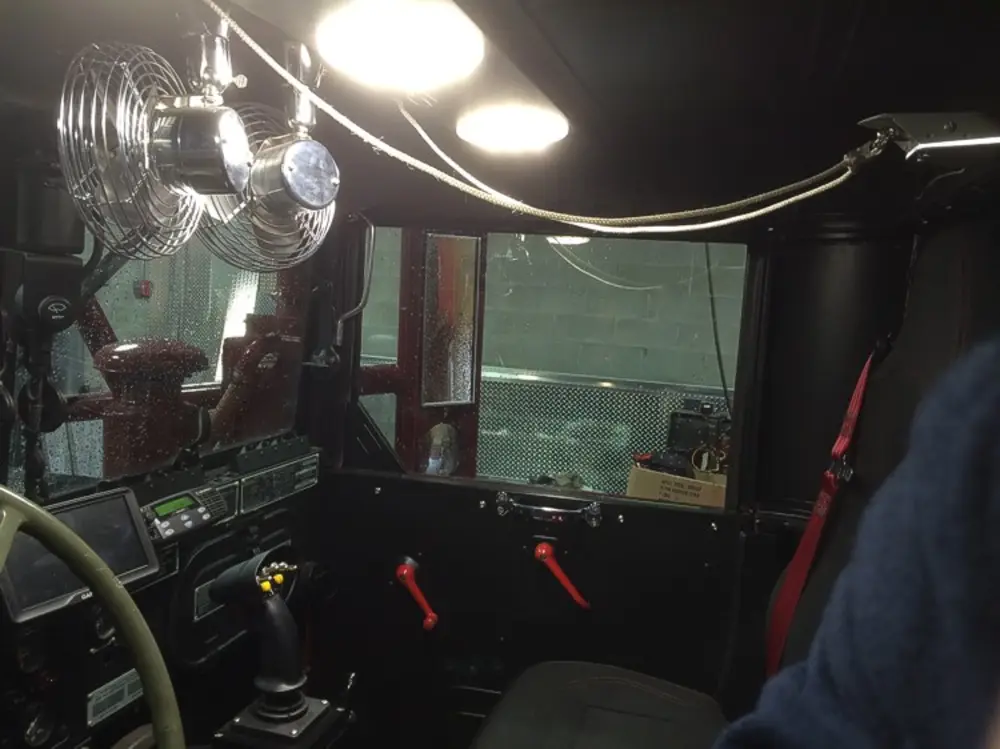 Exterior view of small fire truck showing cab, body compartments, and wheel/tire area.