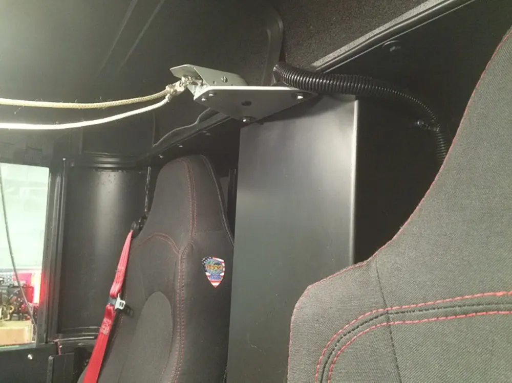 Exterior view of small fire truck showing cab, body compartments, and wheel/tire area.