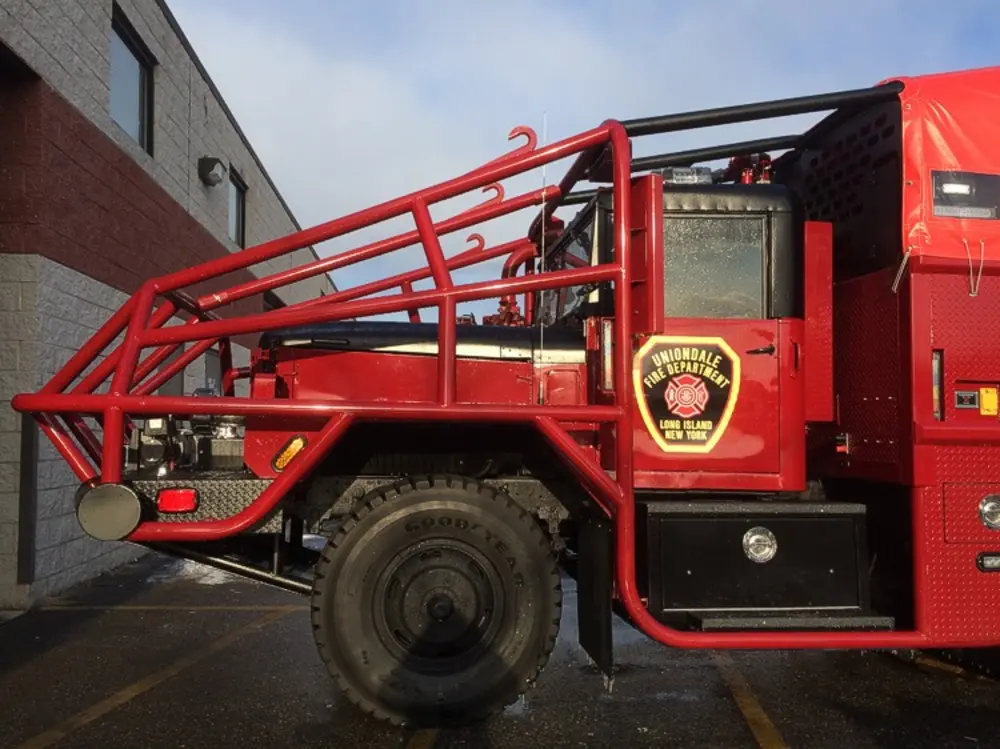 Exterior view of small fire truck showing cab, body compartments, and wheel/tire area.