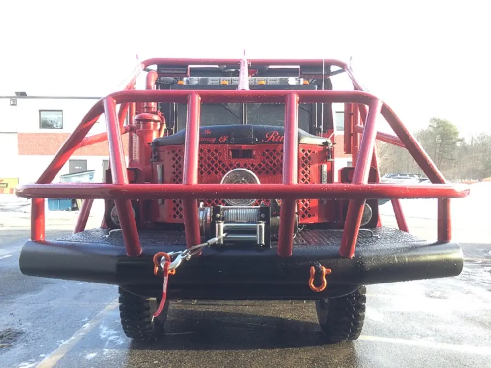 Exterior view of small fire truck showing cab, body compartments, and wheel/tire area.