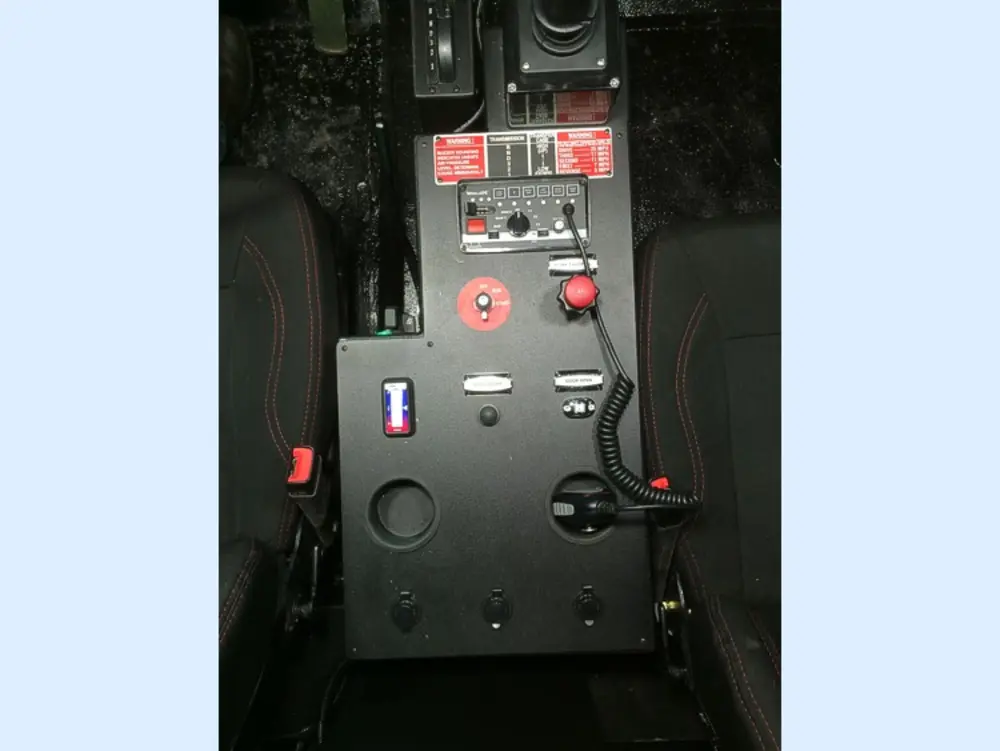 Exterior view of small fire truck showing cab, body compartments, and wheel/tire area.