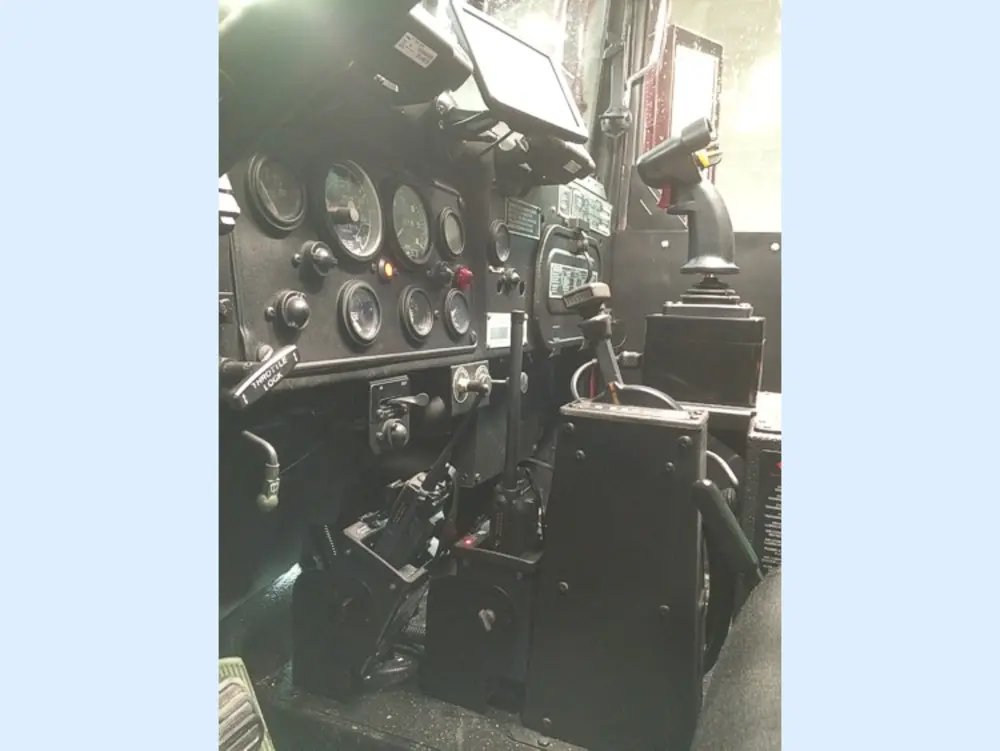 Exterior view of small fire truck showing cab, body compartments, and wheel/tire area.