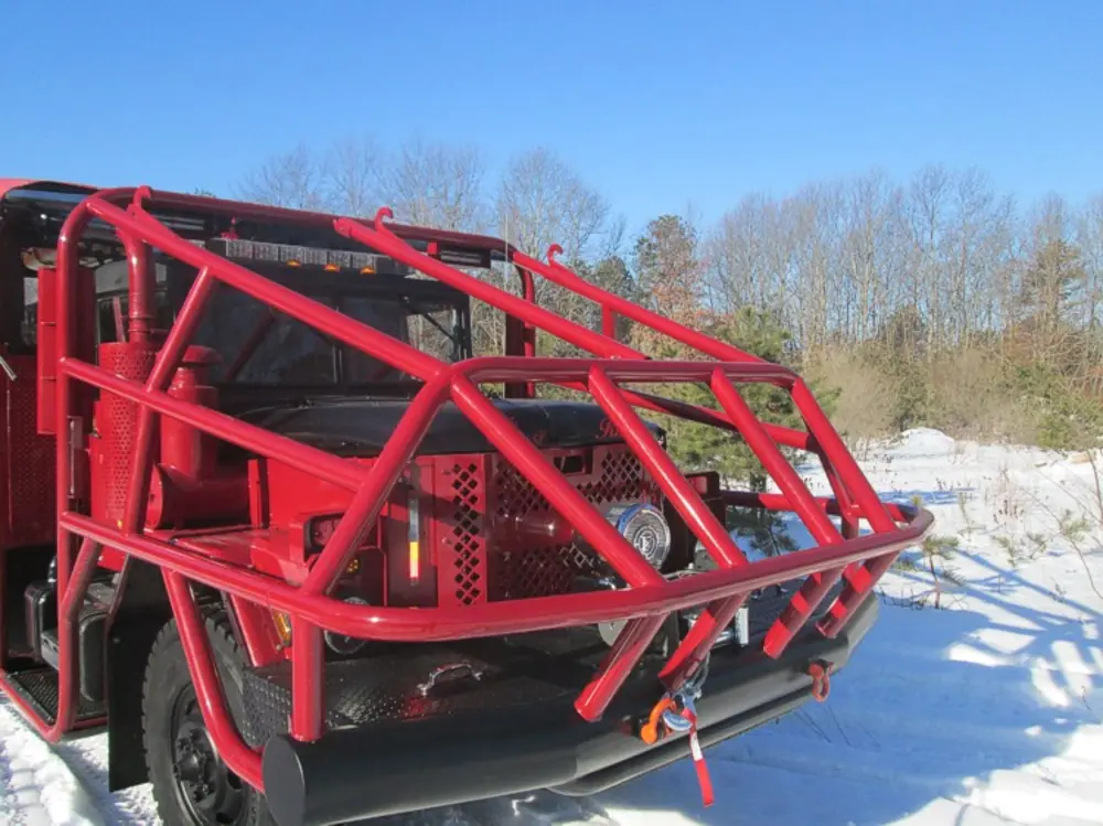 Exterior view of small fire truck showing cab, body compartments, and wheel/tire area.