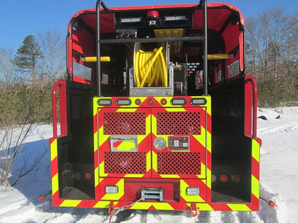 Exterior view of small fire truck showing cab, body compartments, and wheel/tire area.