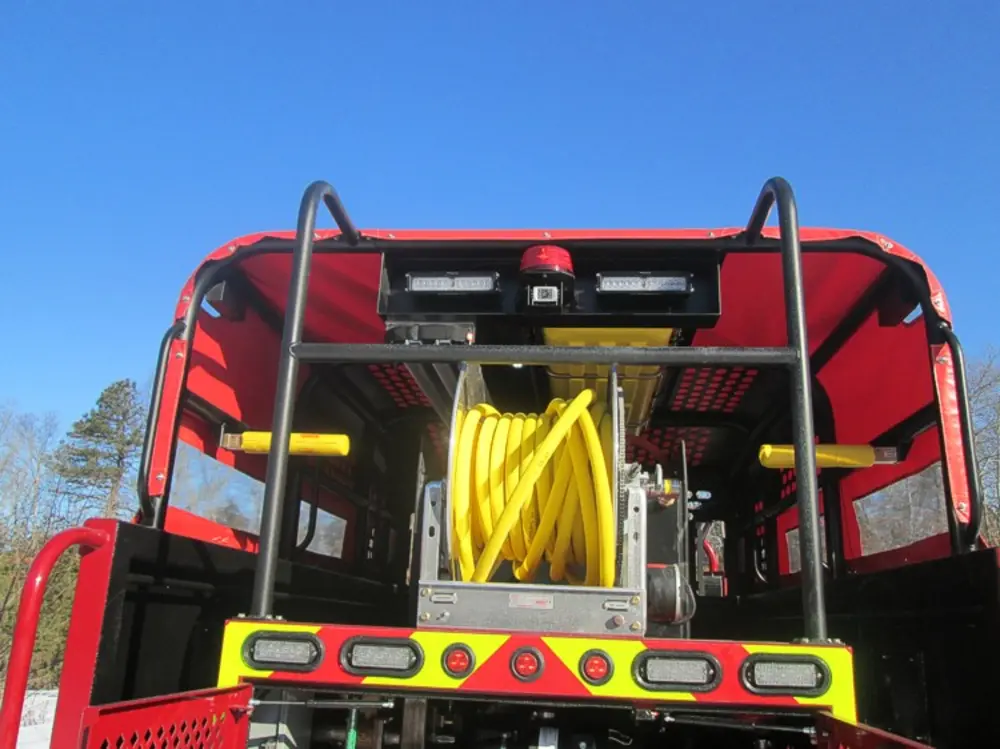 Exterior view of small fire truck showing cab, body compartments, and wheel/tire area.