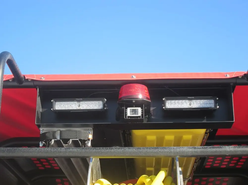Exterior view of small fire truck showing cab, body compartments, and wheel/tire area.