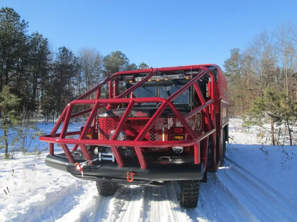 Exterior view of small fire truck showing cab, body compartments, and wheel/tire area.