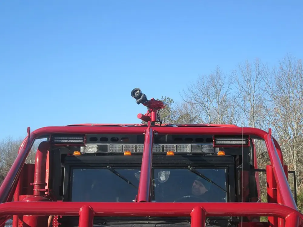 Exterior view of small fire truck showing cab, body compartments, and wheel/tire area.