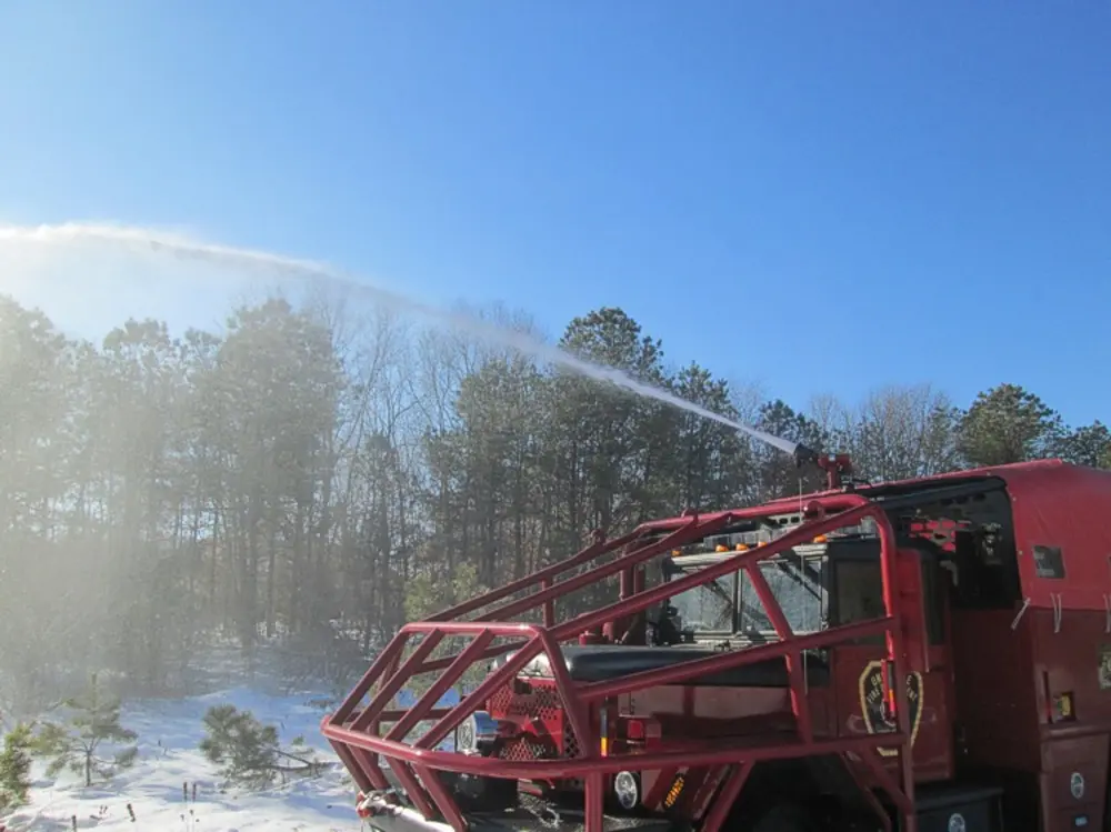 Exterior view of small fire truck showing cab, body compartments, and wheel/tire area.
