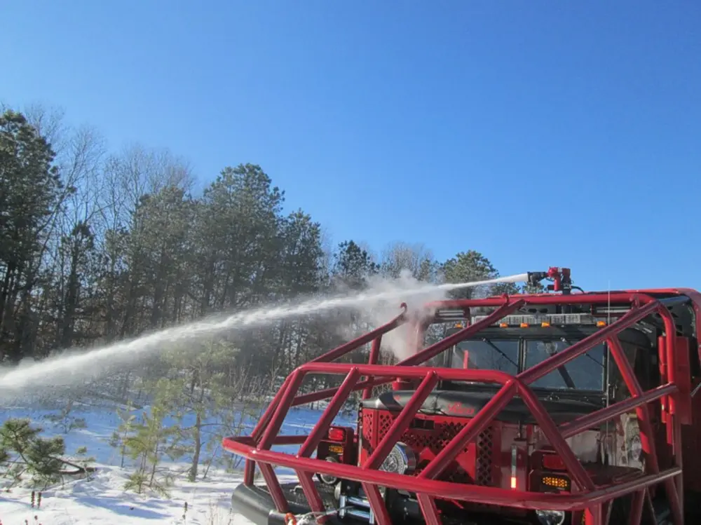 Exterior view of small fire truck showing cab, body compartments, and wheel/tire area.
