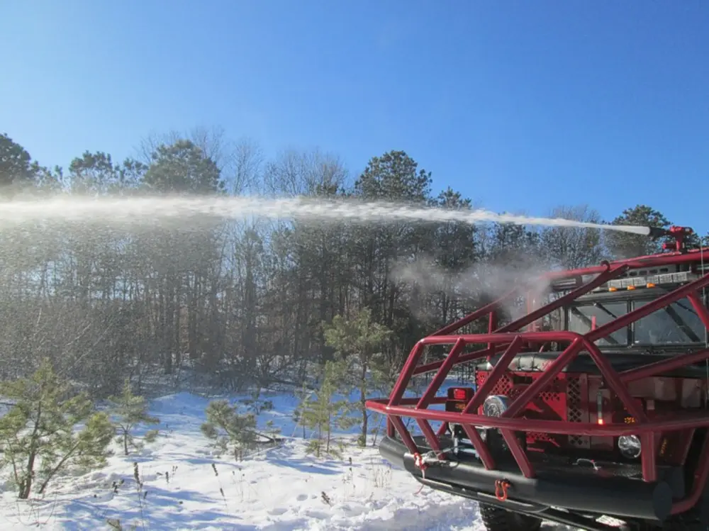 Exterior view of small fire truck showing cab, body compartments, and wheel/tire area.