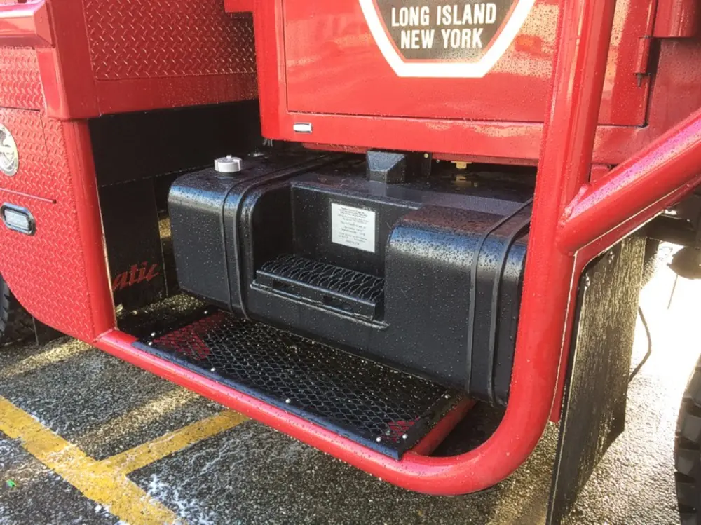 Exterior view of small fire truck showing cab, body compartments, and wheel/tire area.