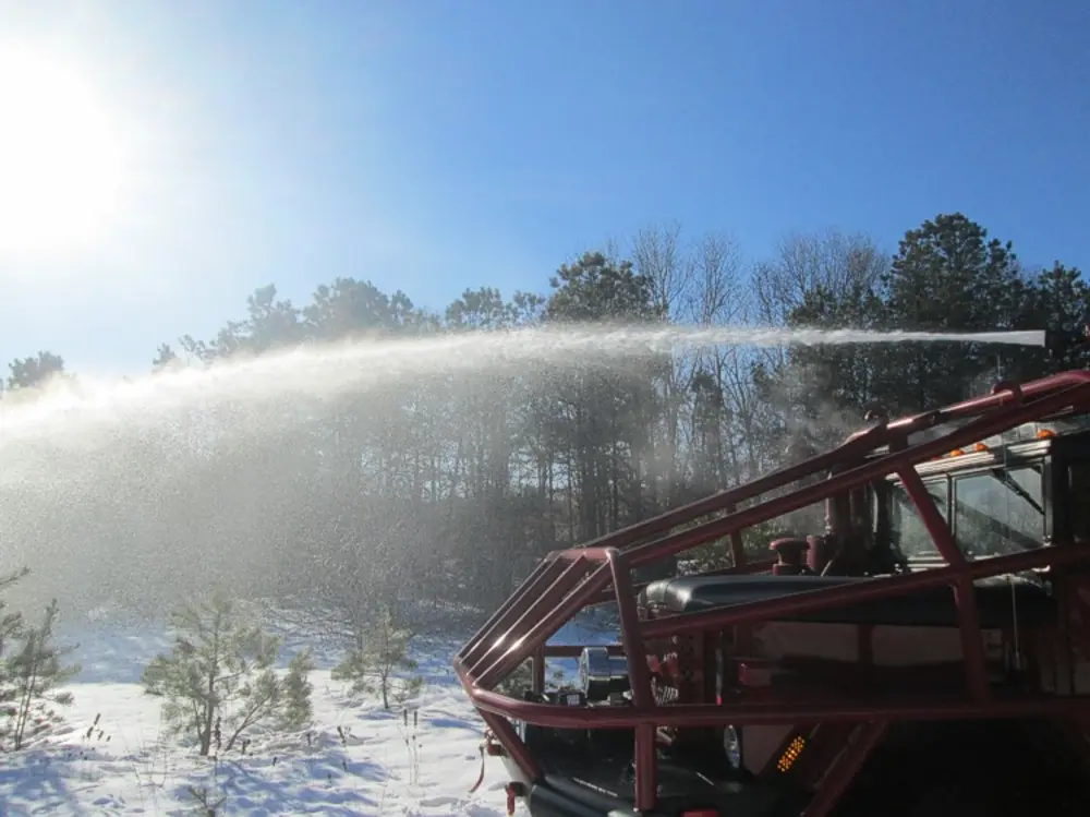 Exterior view of small fire truck showing cab, body compartments, and wheel/tire area.
