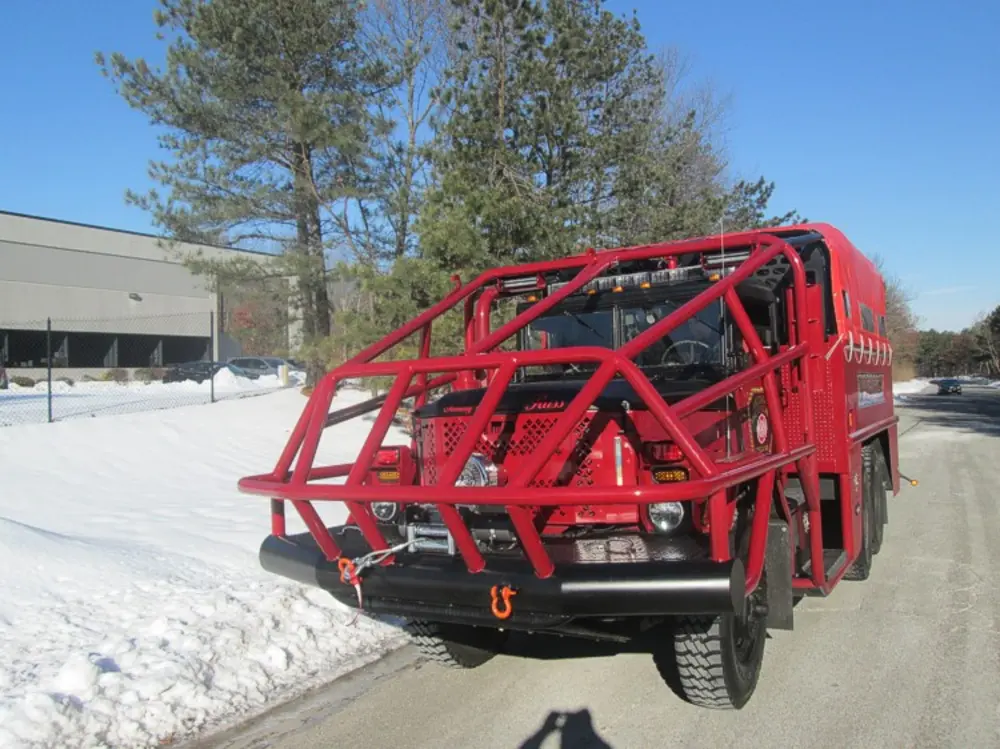 Exterior view of small fire truck showing cab, body compartments, and wheel/tire area.