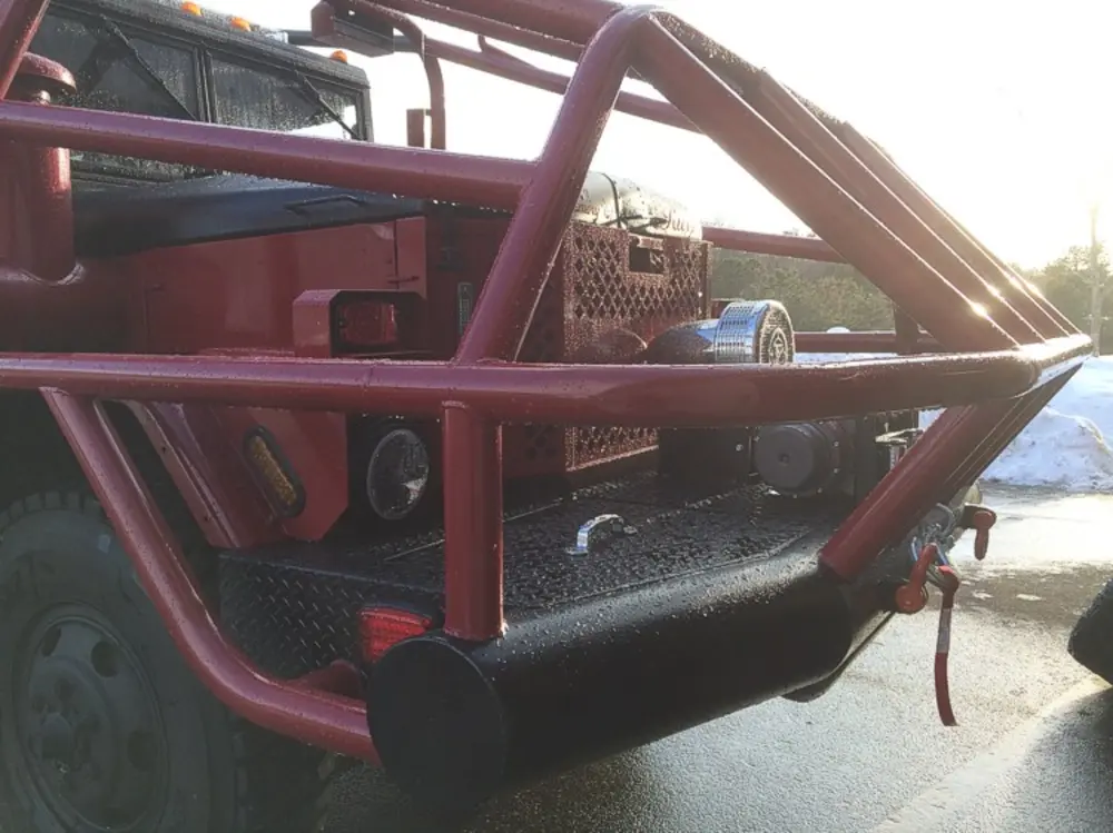 Exterior view of small fire truck showing cab, body compartments, and wheel/tire area.
