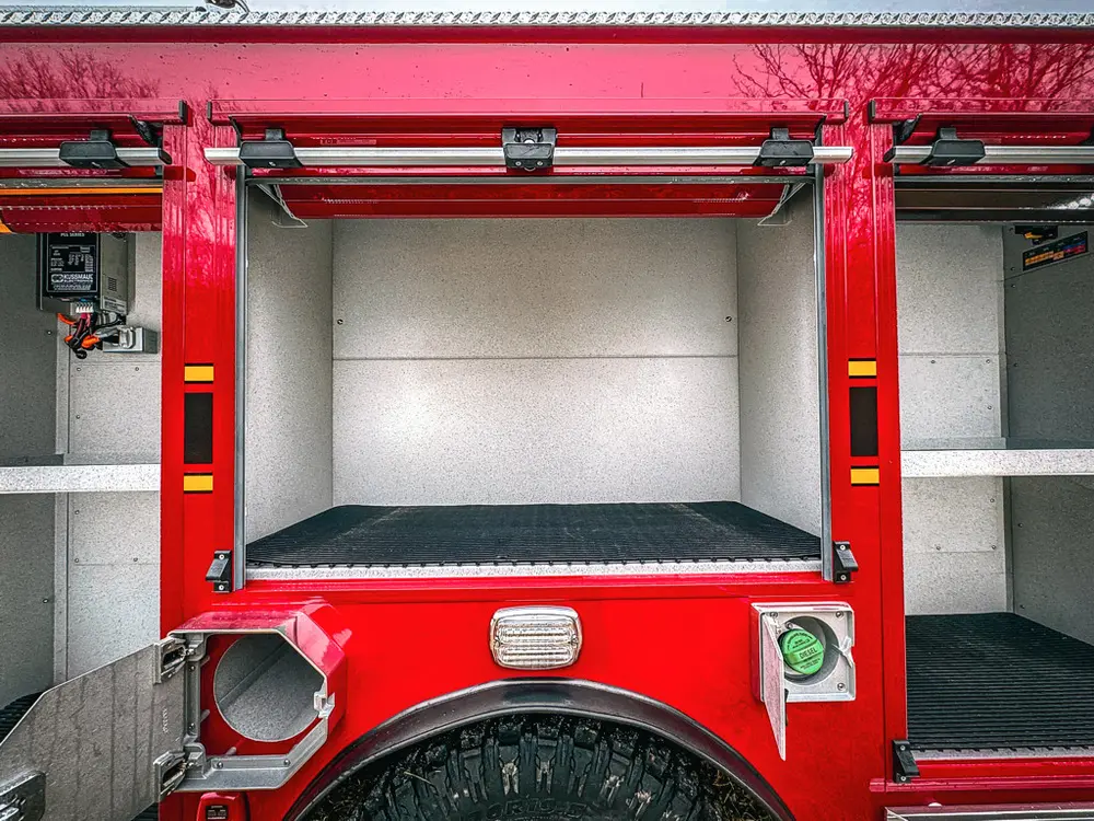 Open lower side compartment with empty bay and black floor mat.