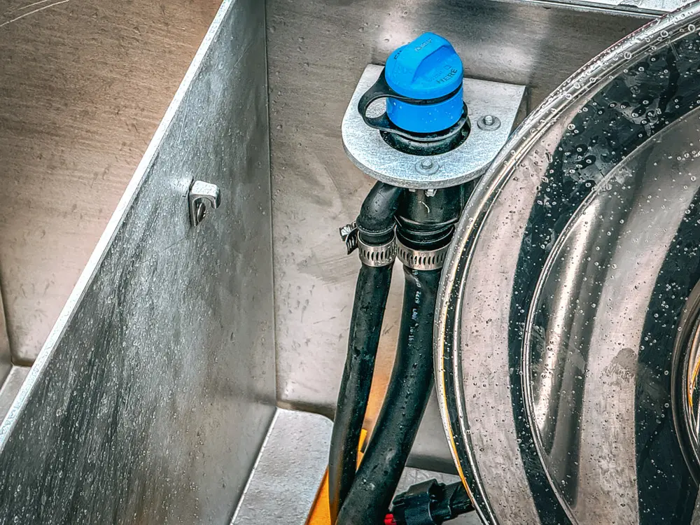 Close-up inside upper deck bay showing blue cap and hose connections.