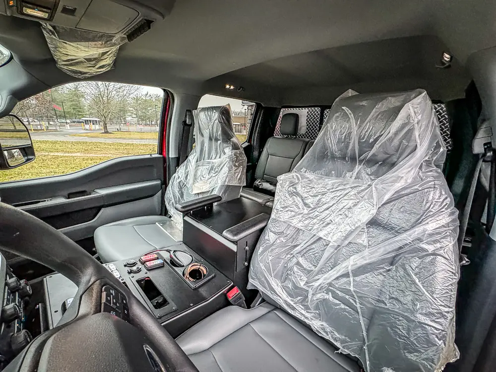 Passenger-side interior with front and rear seats wrapped in plastic.