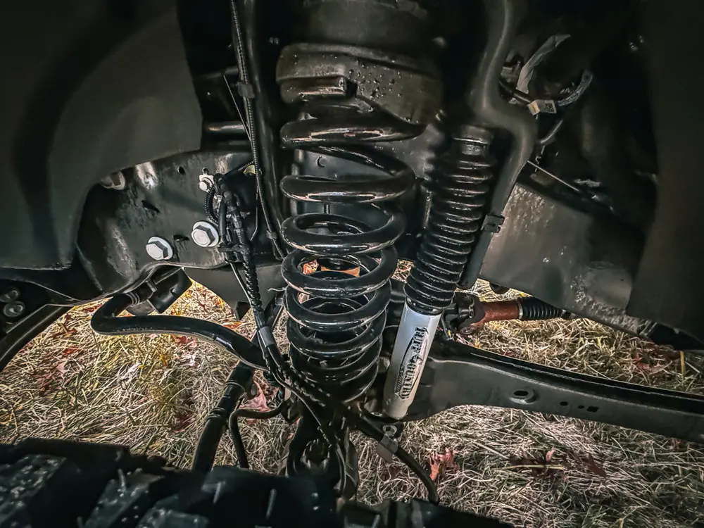 Front suspension close-up inside wheel well showing spring and linkage.