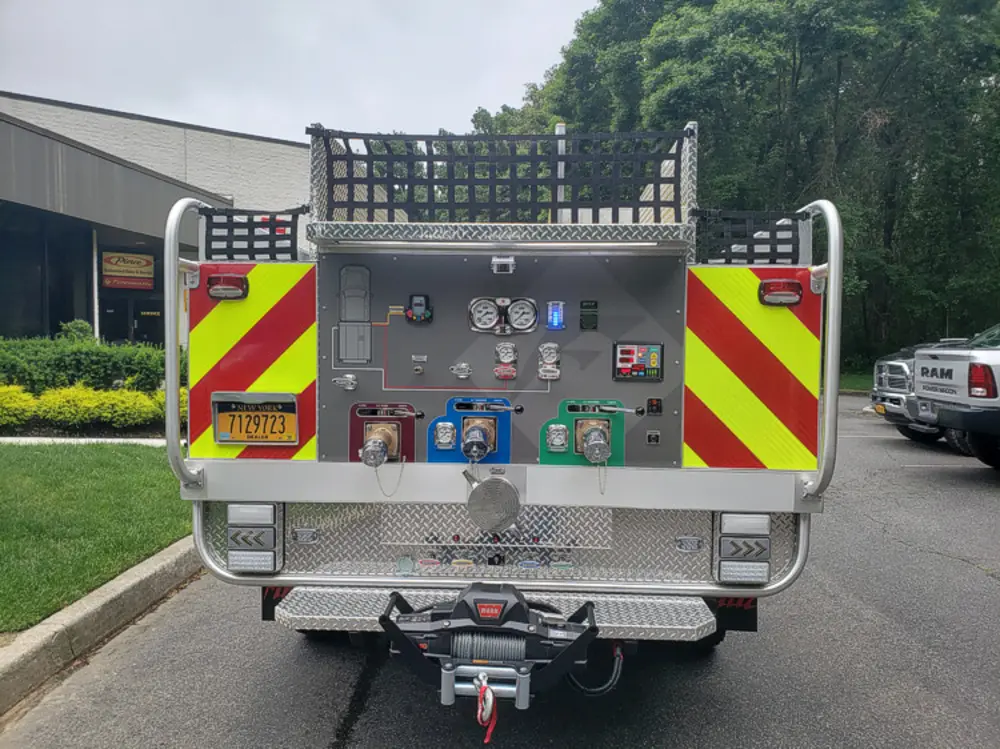 Exterior view of small fire truck showing cab, body compartments, and wheel/tire area.