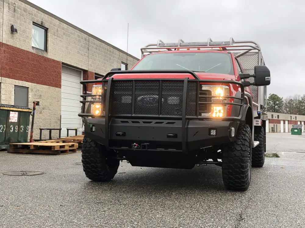 Exterior view of small fire truck showing cab, body compartments, and wheel/tire area.