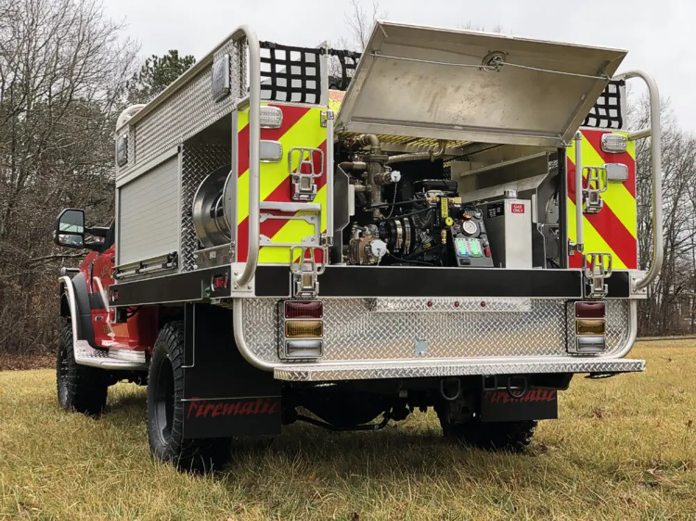 Exterior view of small fire truck showing cab, body compartments, and wheel/tire area.