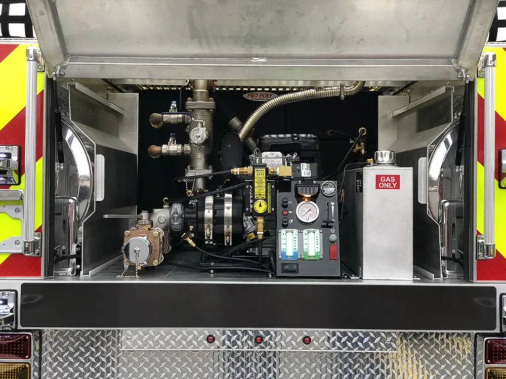 Exterior view of small fire truck showing cab, body compartments, and wheel/tire area.