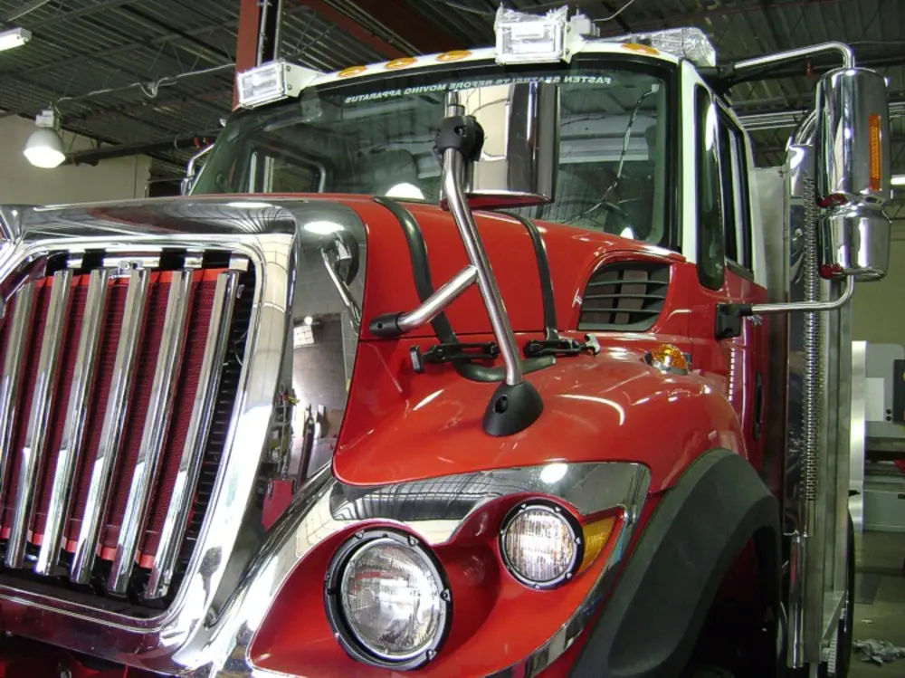 Exterior view of small fire truck showing cab, body compartments, and wheel/tire area.