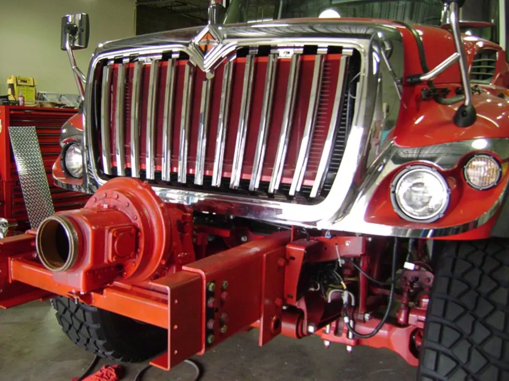 Exterior view of small fire truck showing cab, body compartments, and wheel/tire area.