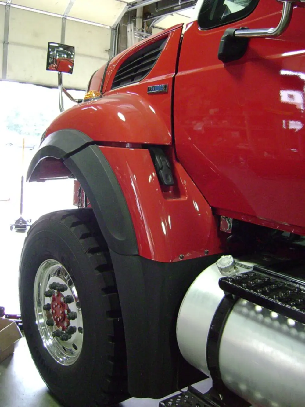 Exterior view of small fire truck showing cab, body compartments, and wheel/tire area.