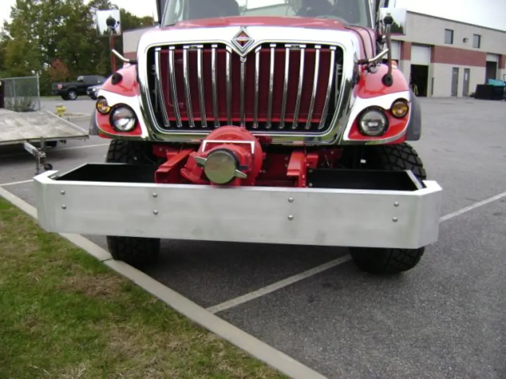 Exterior view of small fire truck showing cab, body compartments, and wheel/tire area.