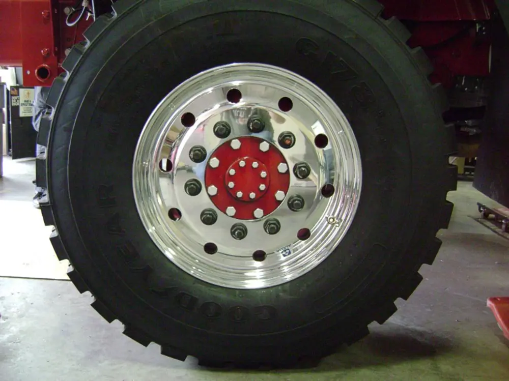 Exterior view of small fire truck showing cab, body compartments, and wheel/tire area.