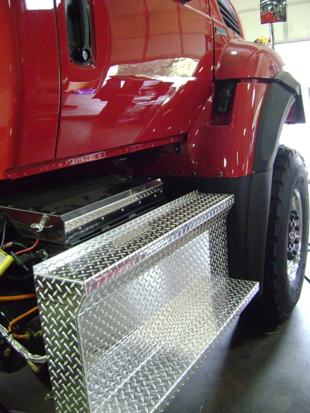Exterior view of small fire truck showing cab, body compartments, and wheel/tire area.
