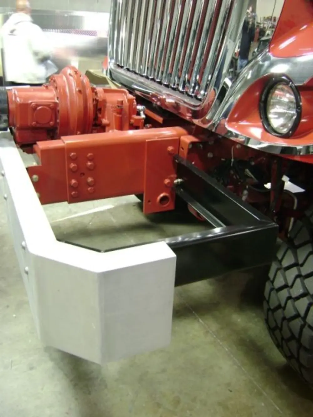 Exterior view of small fire truck showing cab, body compartments, and wheel/tire area.