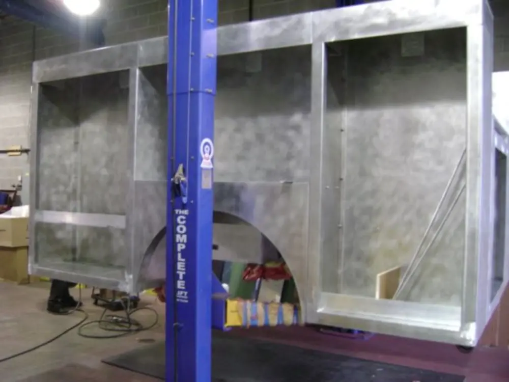 Exterior view of small fire truck showing cab, body compartments, and wheel/tire area.