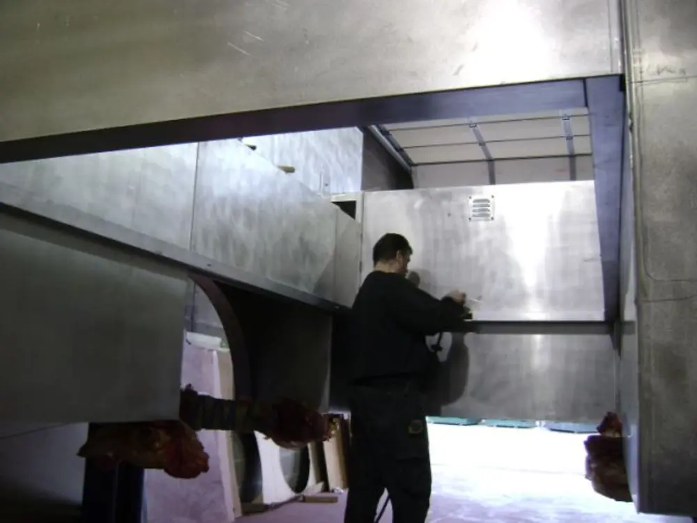 Exterior view of small fire truck showing cab, body compartments, and wheel/tire area.