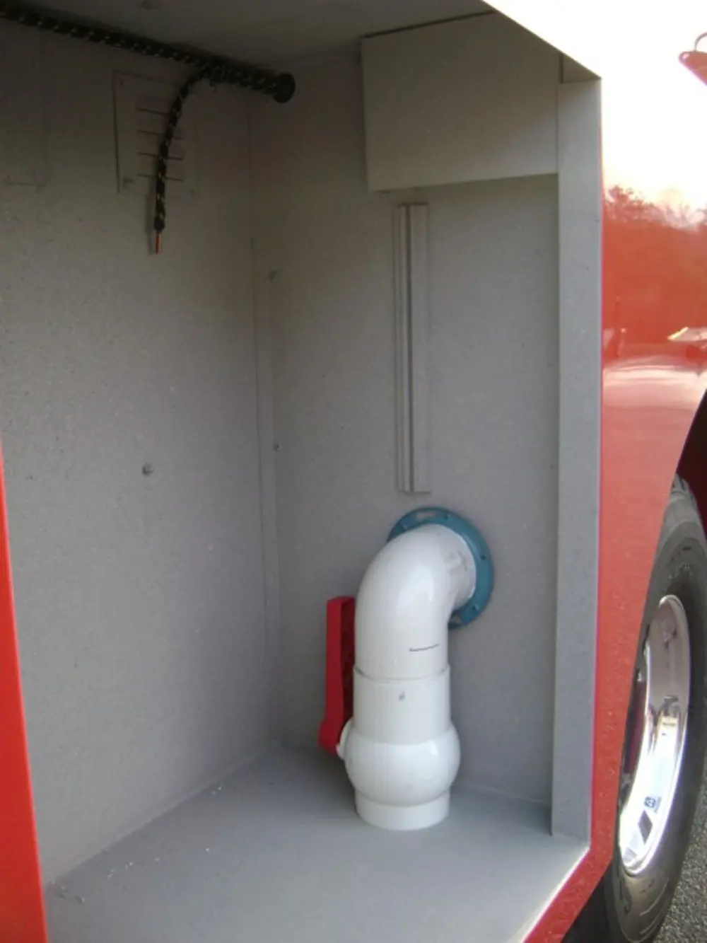 Exterior view of small fire truck showing cab, body compartments, and wheel/tire area.