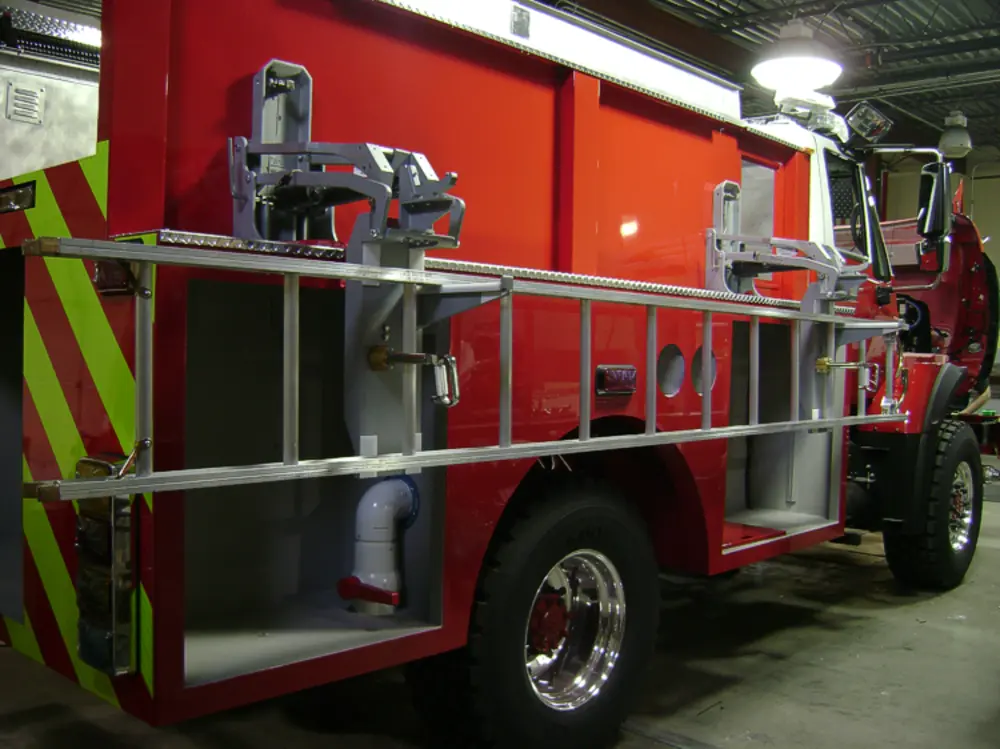 Exterior view of small fire truck showing cab, body compartments, and wheel/tire area.