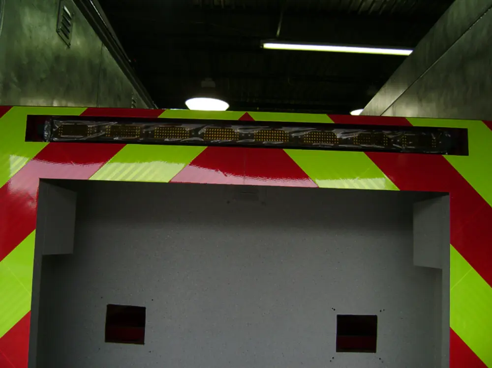 Exterior view of small fire truck showing cab, body compartments, and wheel/tire area.